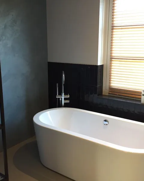 Badkamer met vrijstaand bad en betonlook wand