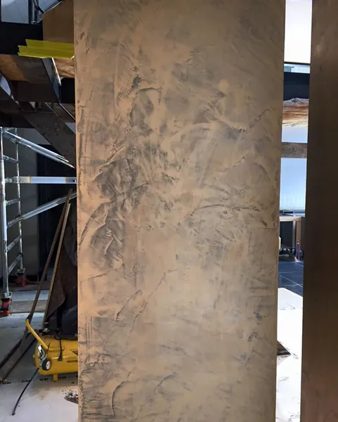 Zuil met een decoratieve structuurafwerking naast een houten balk
