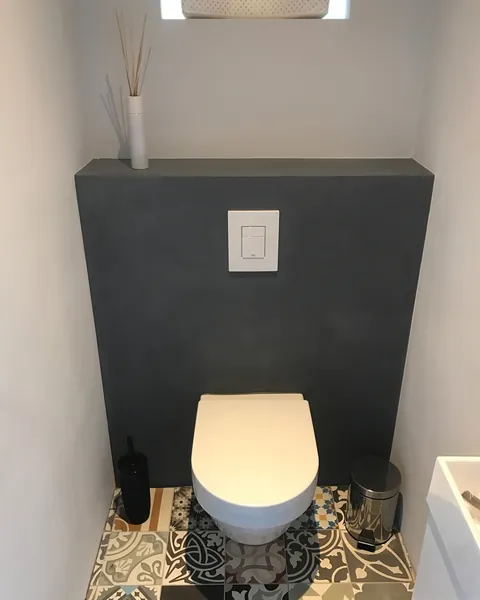 Toilet met een antracietkleurige betonlook wand